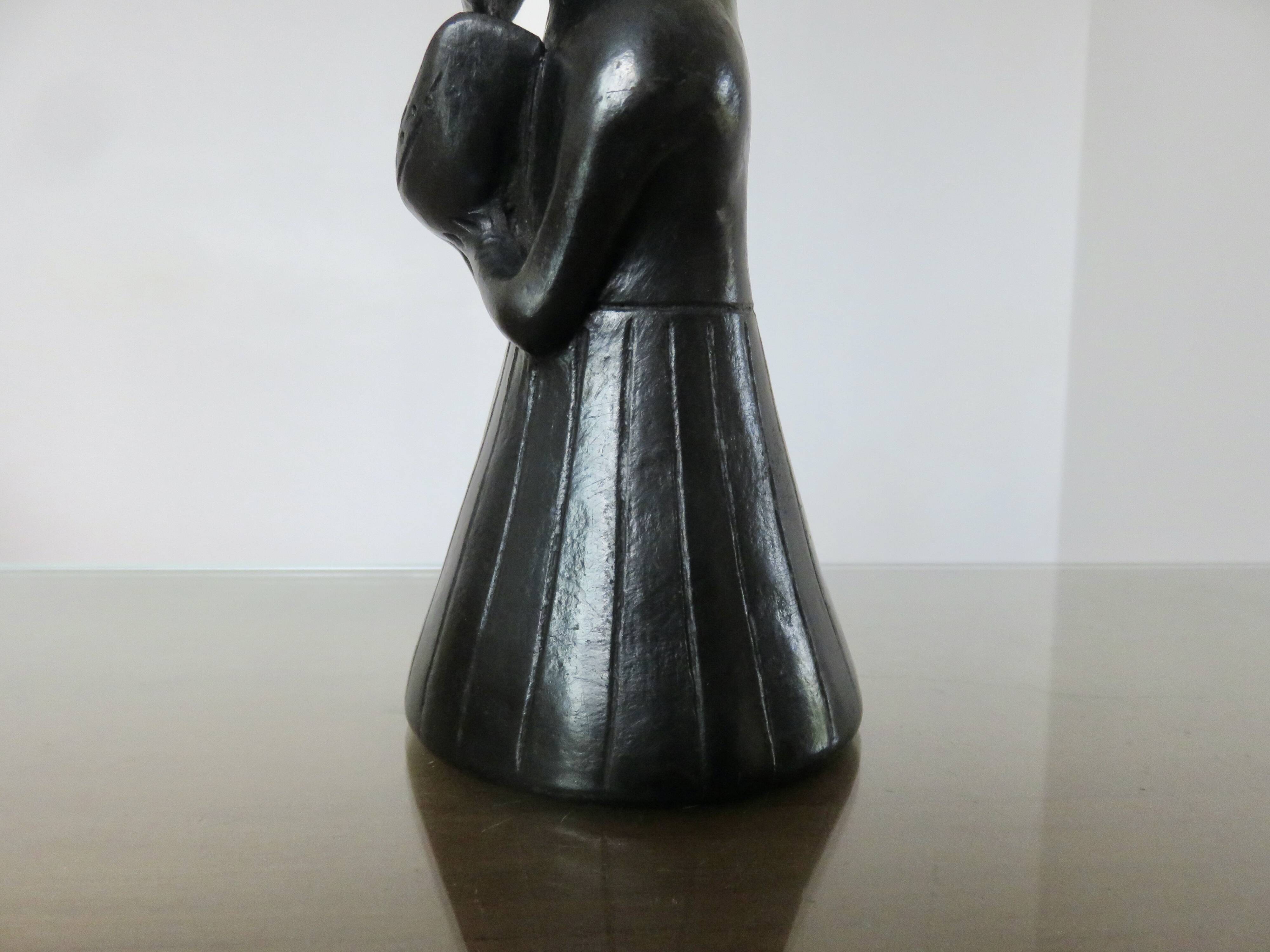 Matte black ceramic sculpture representing a female tribal figure.