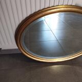 Large and elegant oval gilded mirror with its beveled glass