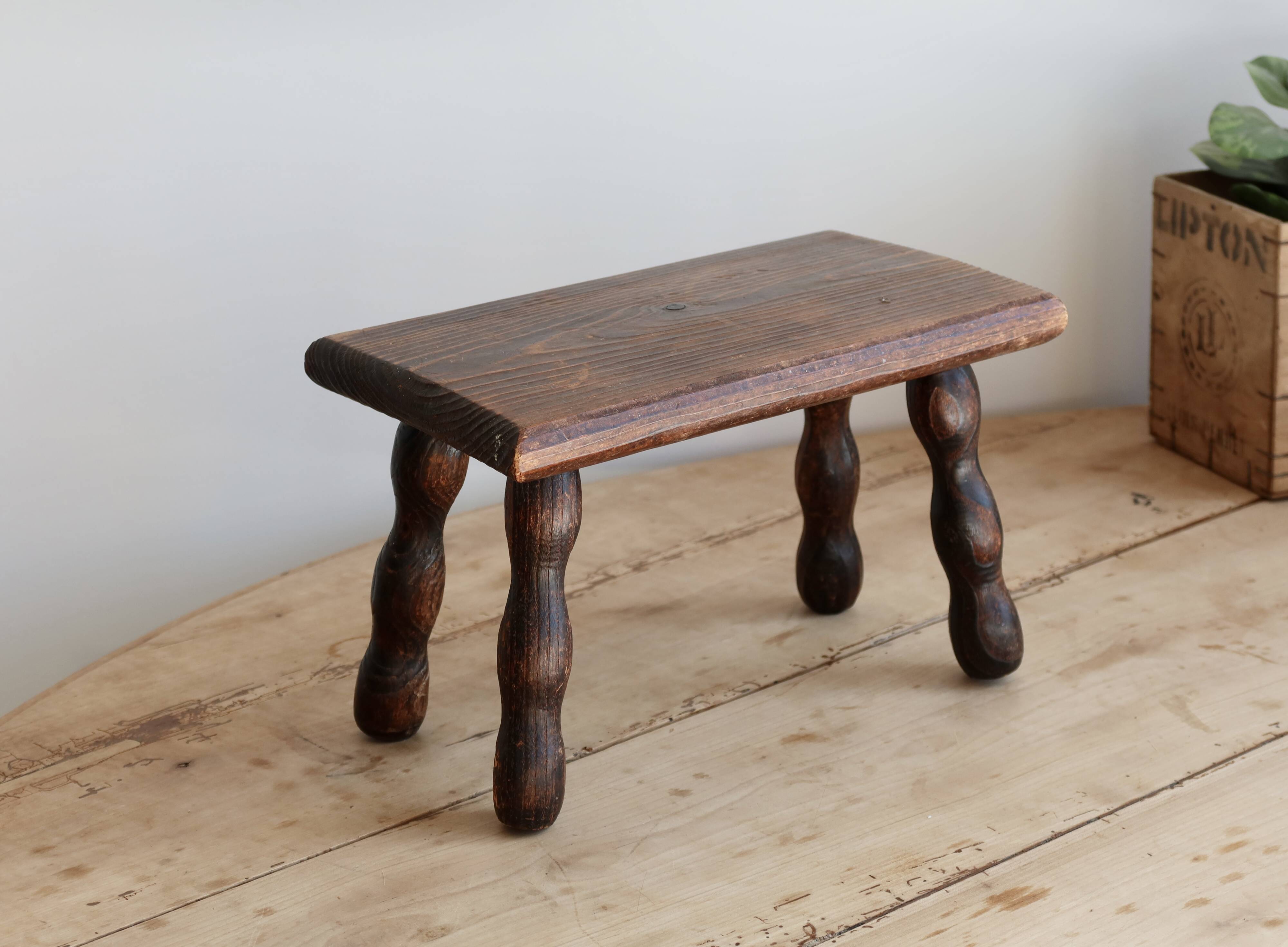 Vintage rectangular stool in dark wood with turned legs.