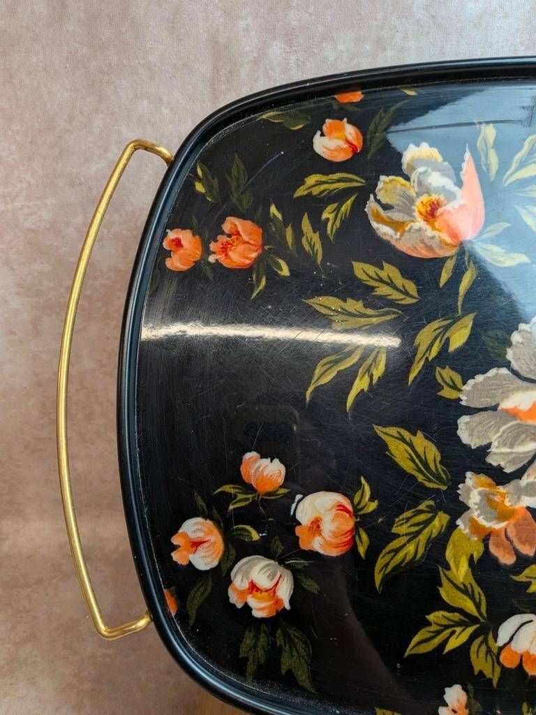 Large vintage 1960s platter with floral decoration on a black background and golden handles.