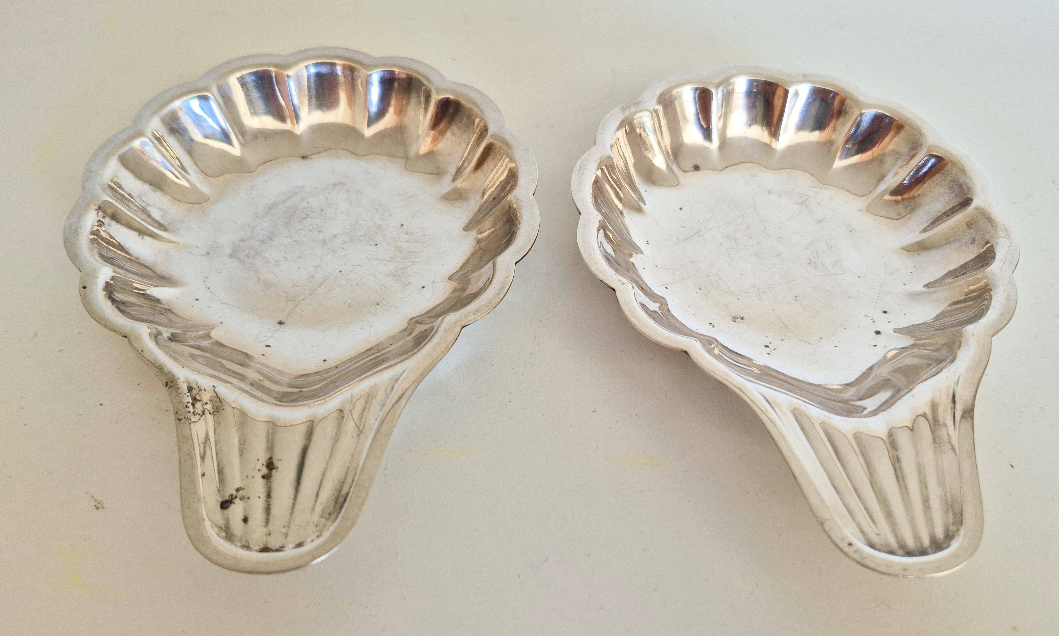 Silver-plated shell-shaped butter dishes, in the shape of a scallop shell.
