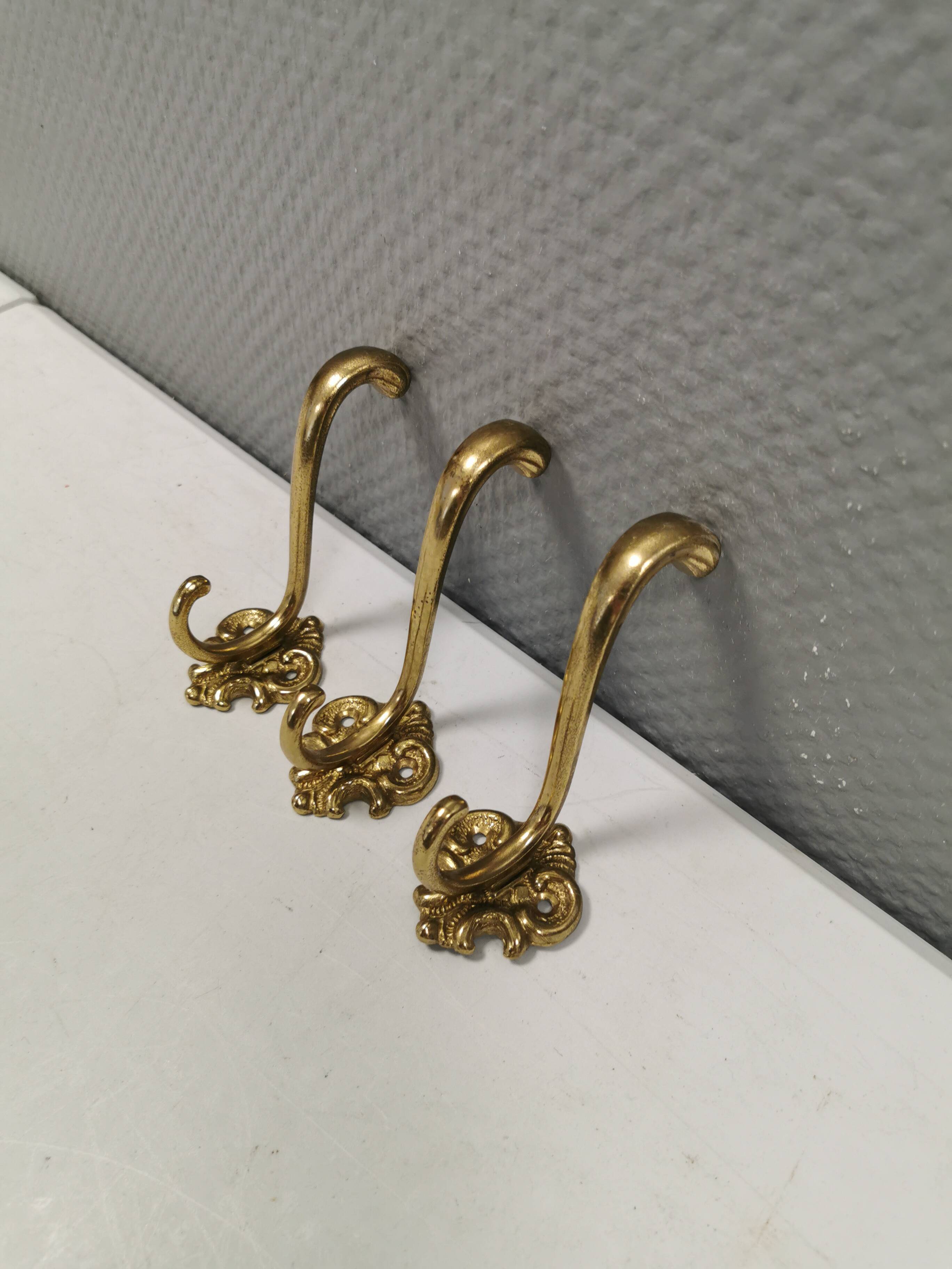Three old and beautiful brass hooks with decorative motifs