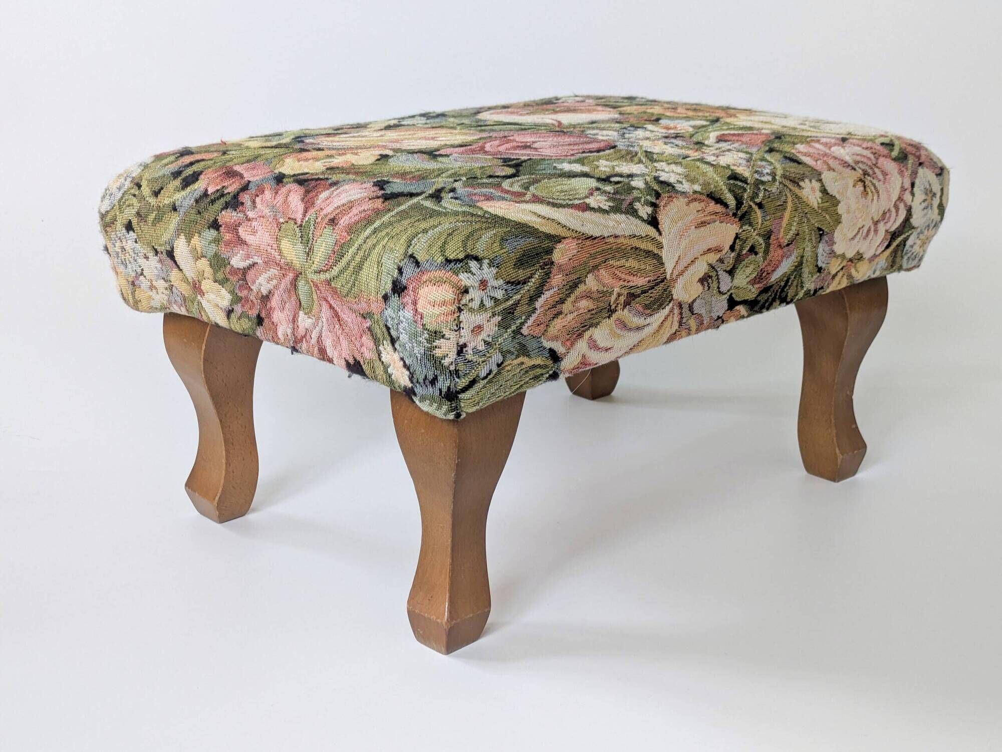 Large vintage upholstered footstool with curved legs.