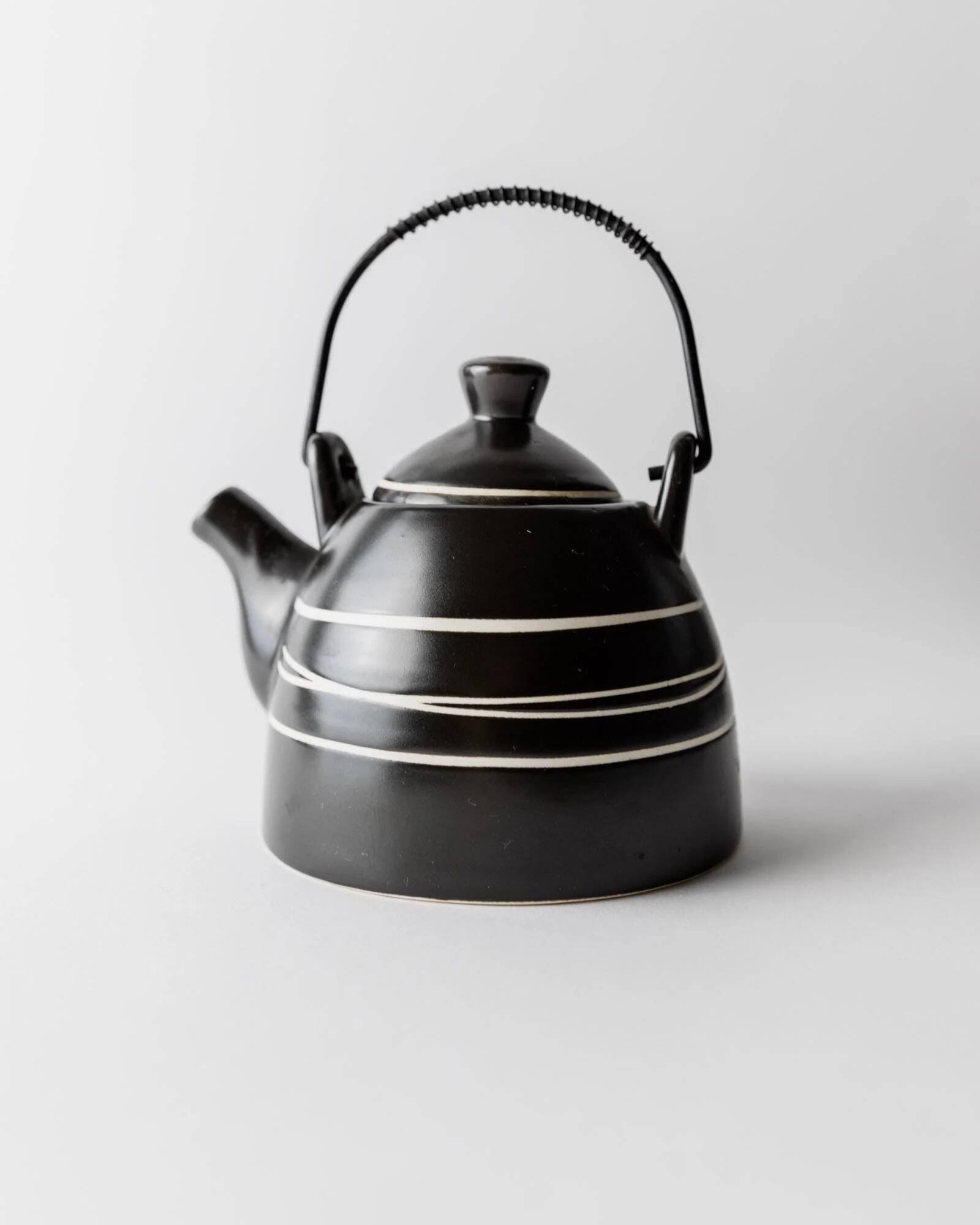 Vintage ceramic teapot from the 1980s, black with white stripes and a metal handle.