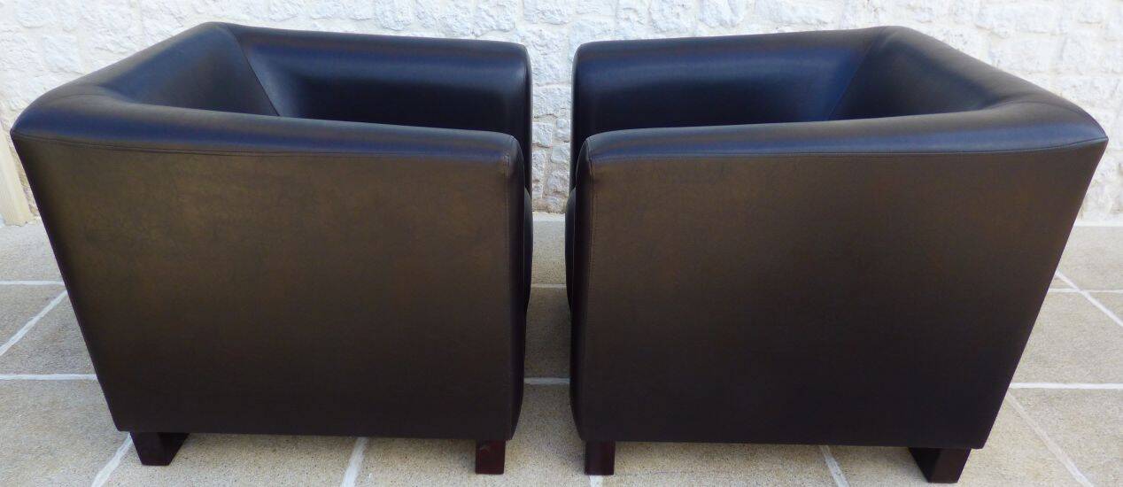 2 club armchairs with a chocolate faux leather seat and backrest and wooden legs.