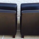 2 club armchairs with a chocolate faux leather seat and backrest and wooden legs.