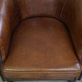 Subtle, neat sheepskin leather club armchair with a fixed seat cushion in a deep, dark cognac color