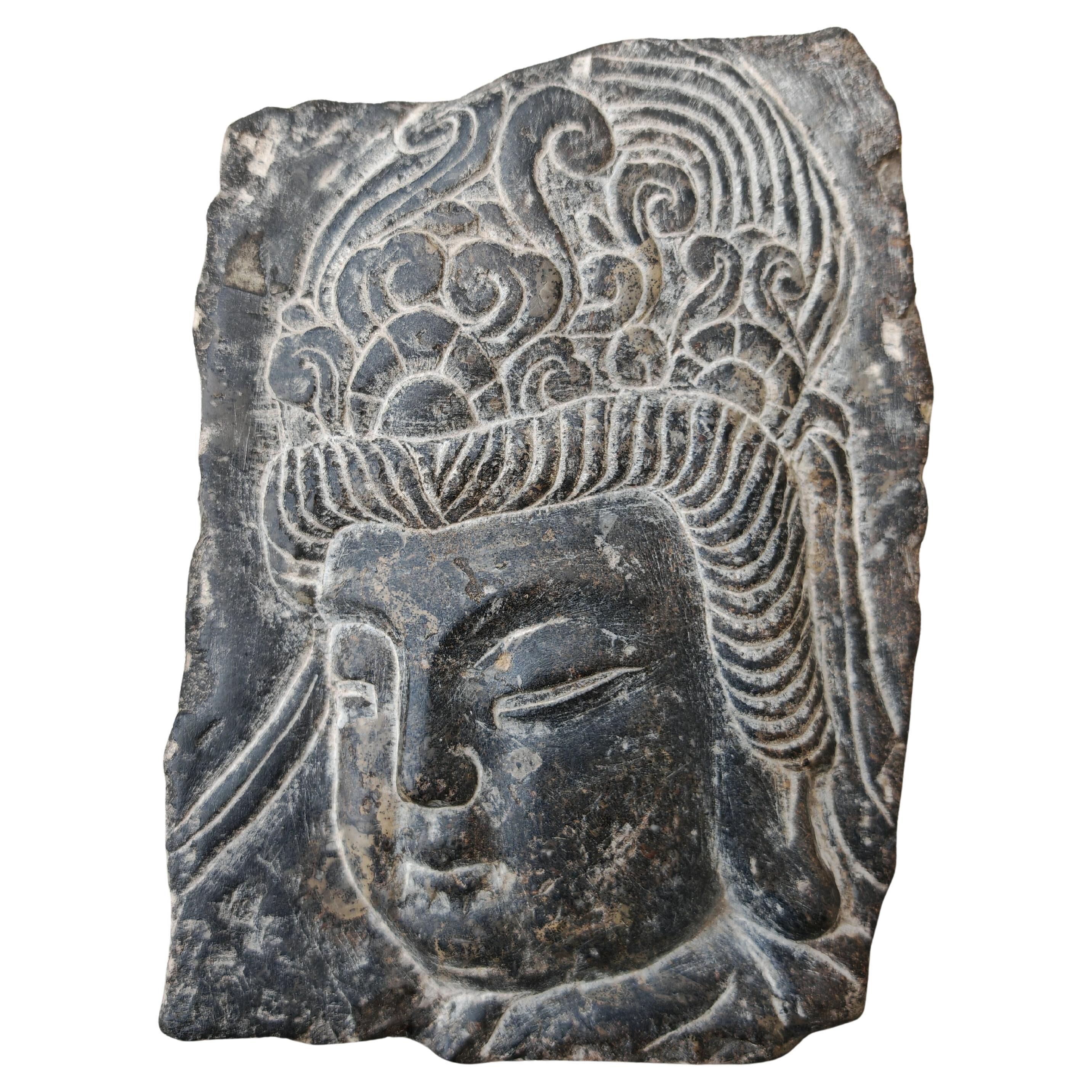 Antique portrait of Buddha hand-carved in stone, 19th century.