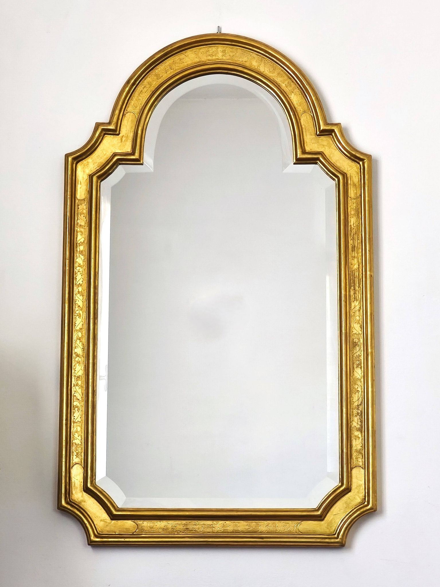 Florentine arched mirror in gilded wood with gold leaf.