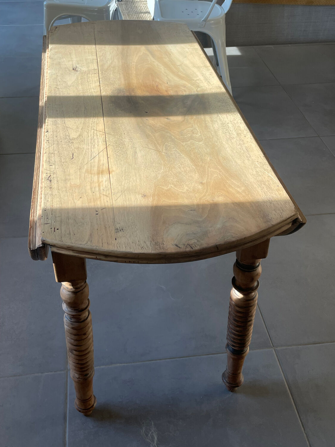 Oval wooden table with drop-leaf edges.