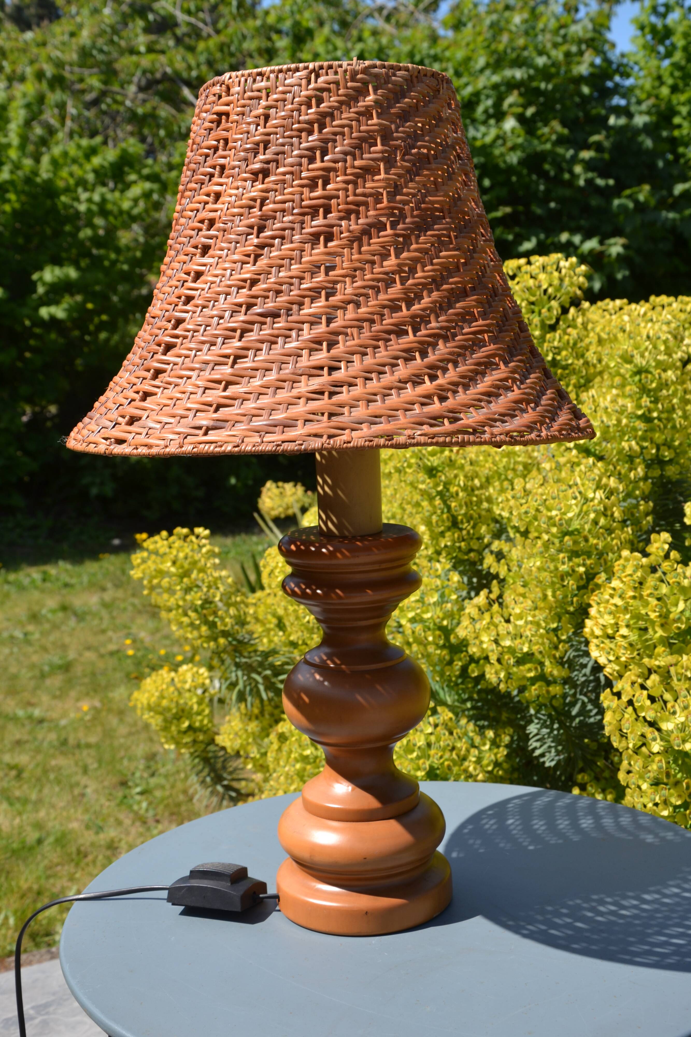 Large wooden lamp with a woven rattan shade.
