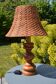 Large wooden lamp with a woven rattan shade.