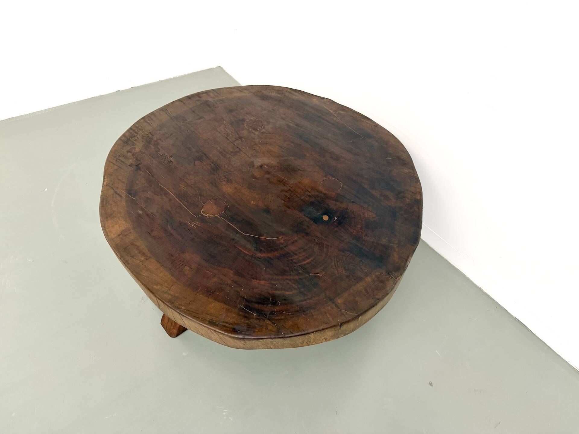 Brutalist coffee table in solid teak, monolithic slab, tripod base.