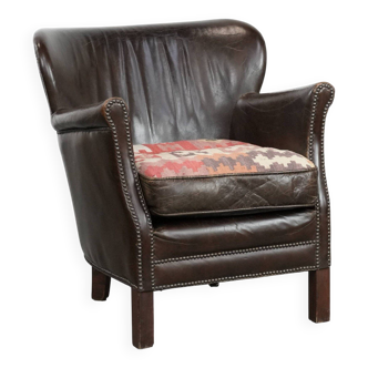 Fauteuil marron en cuir de vache avec un coussin de siège Kilim réversible.