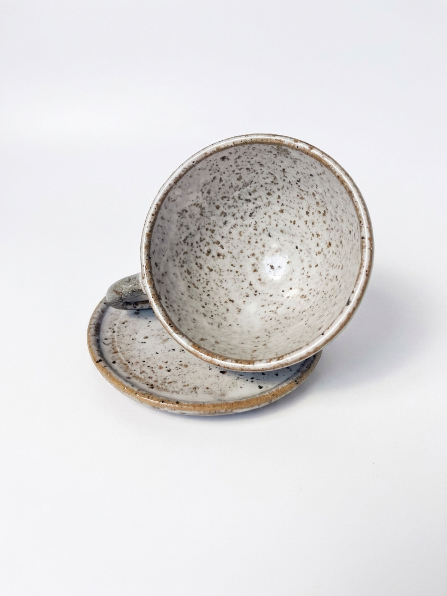 Handcrafted stoneware cup and its saucer – Speckled glaze