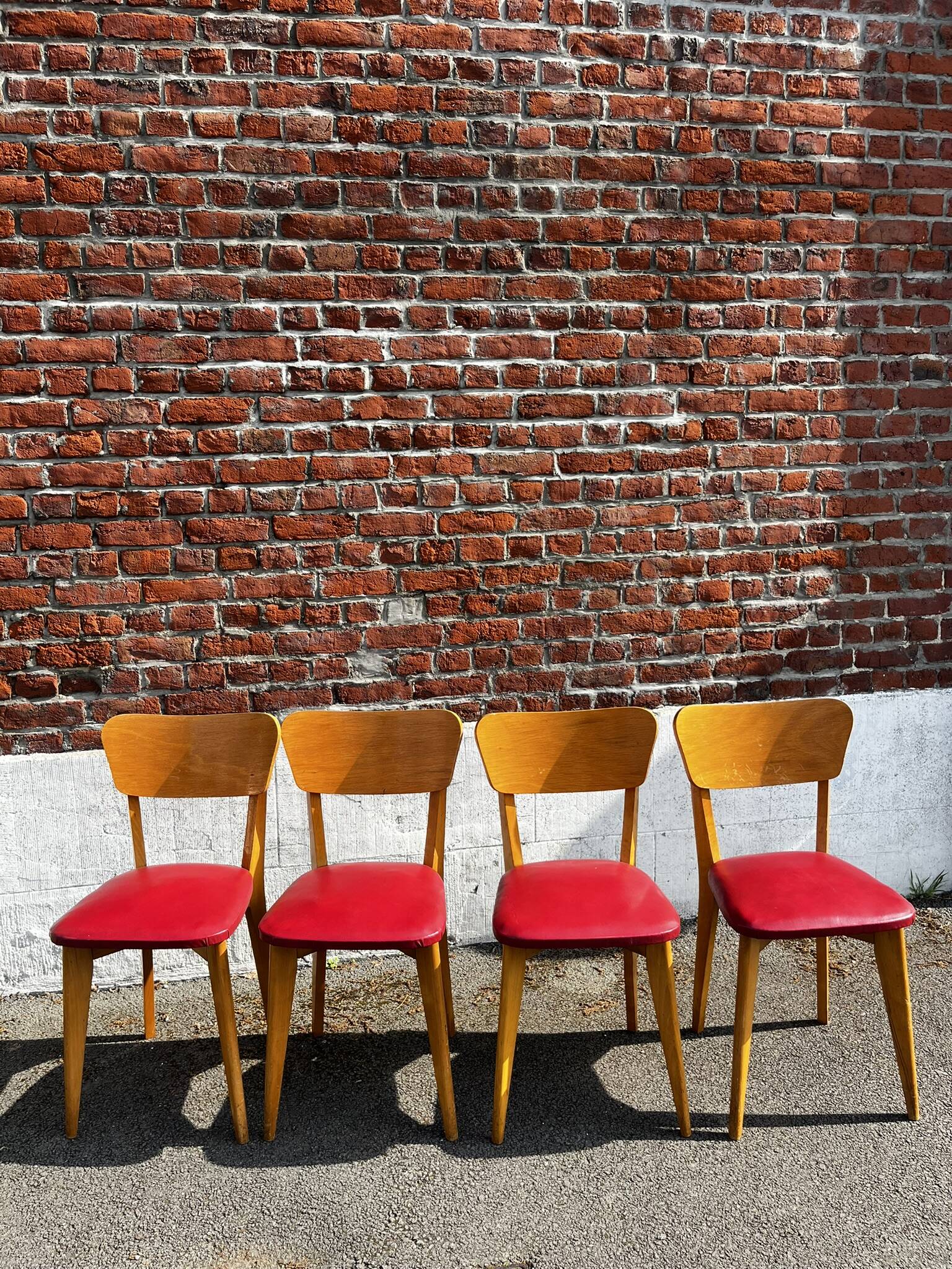 Set of 4 vintage bistro chairs in wood and red faux leather, with splayed legs.