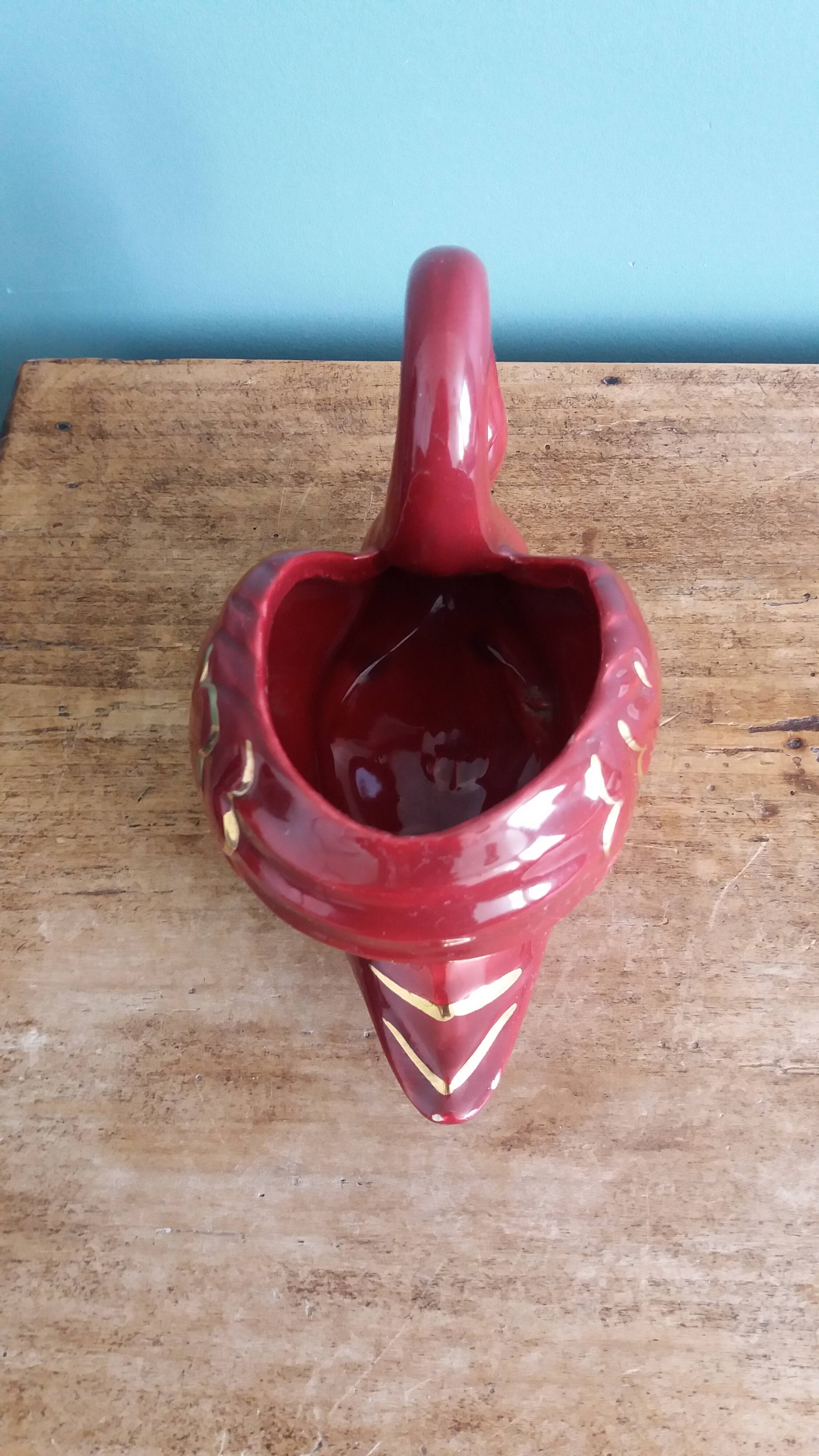 Poet Laval swan hides zoomorphic pot in burgundy ceramic.