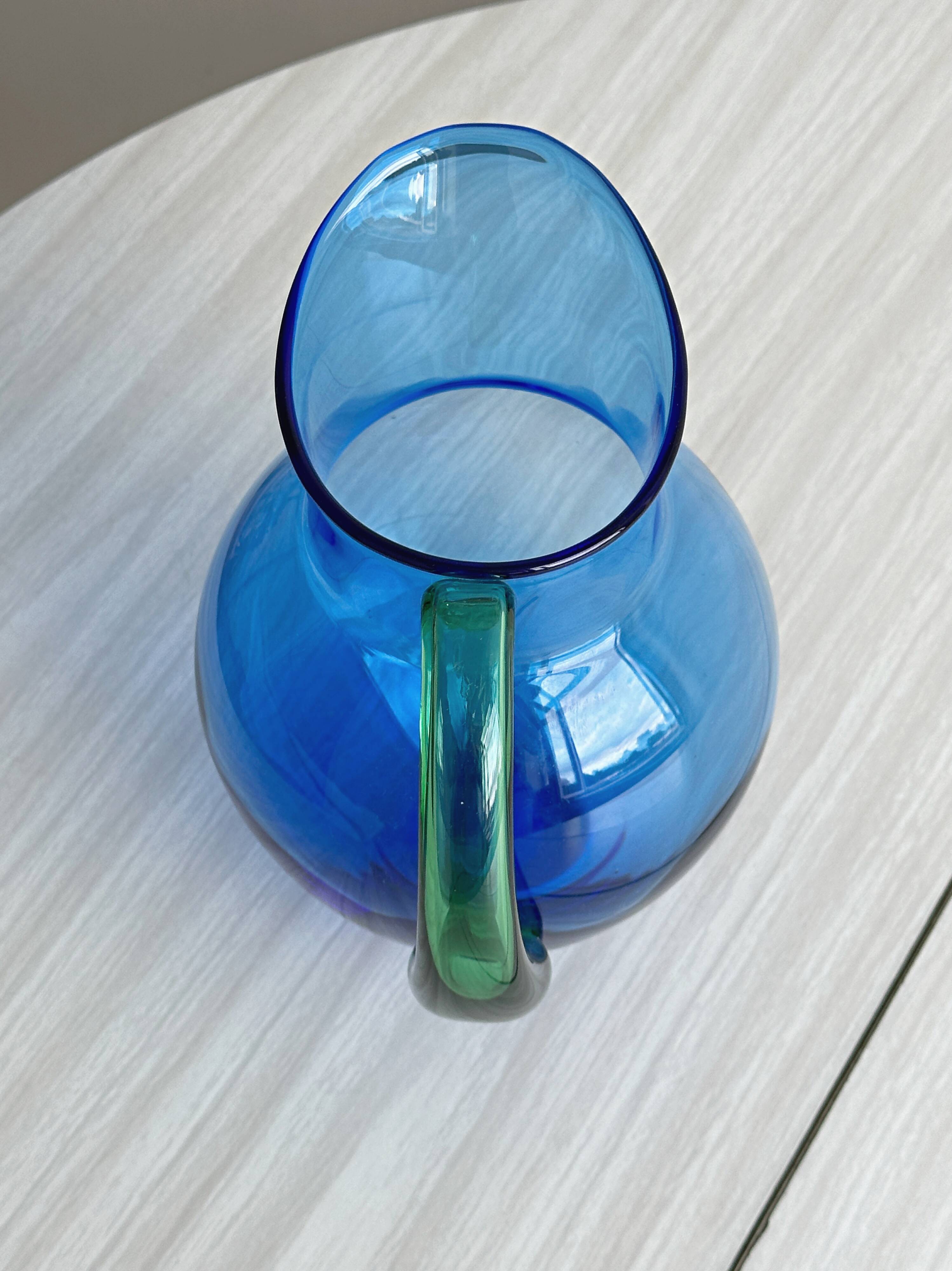 Translucent blue glass jug with a green handle.
