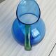 Translucent blue glass jug with a green handle.