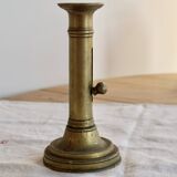 Antique brass candlestick with a push button.