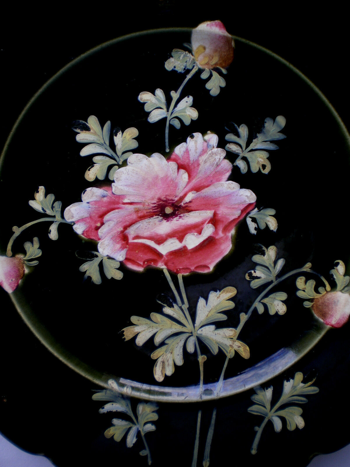 Old plate decorated with anemones or poppies on a black background