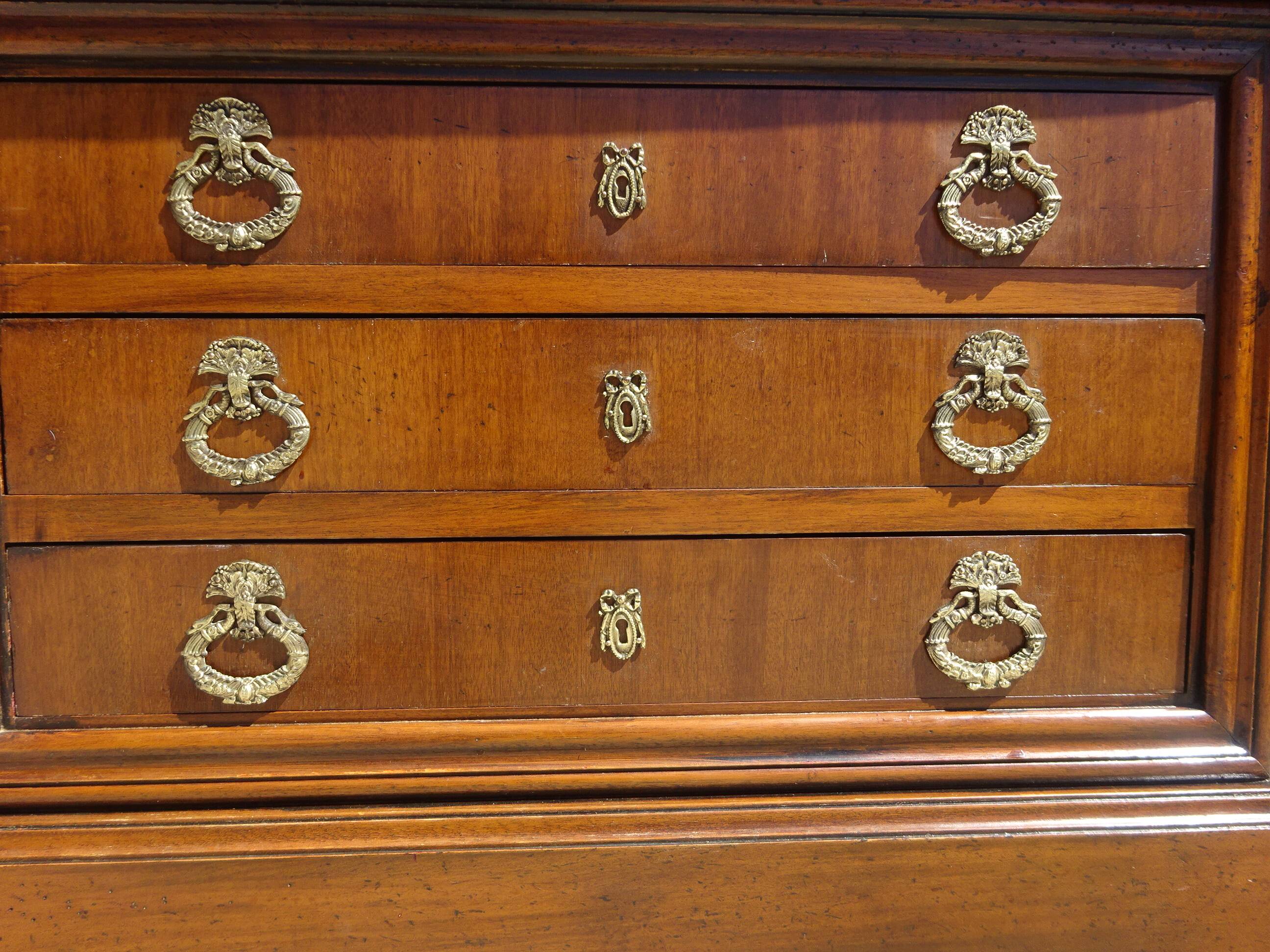 Chest of drawers with decorated handles in the Louis XVI style.