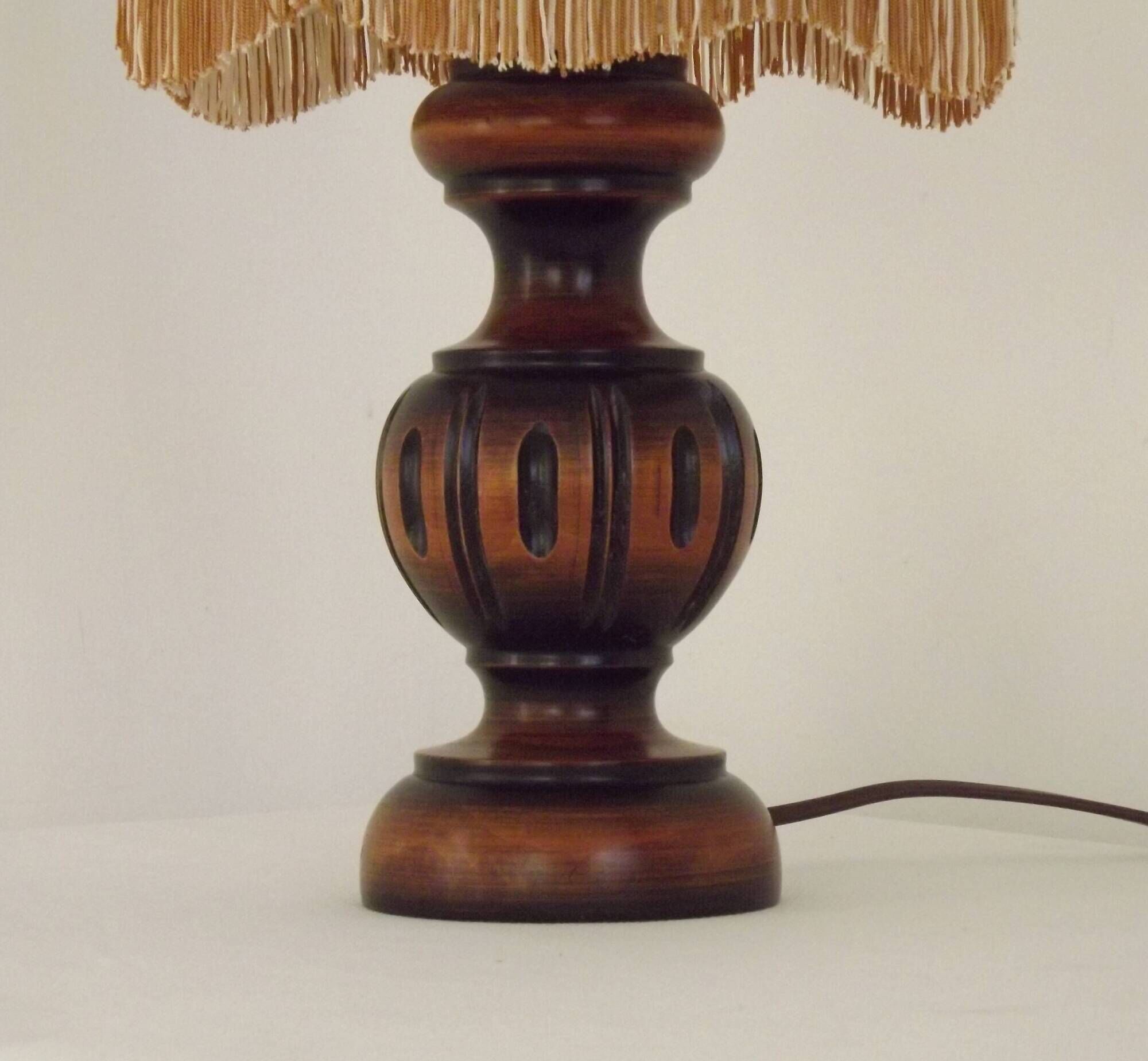 Mid-century French table lamp made of turned carved wood with a fringed shade.