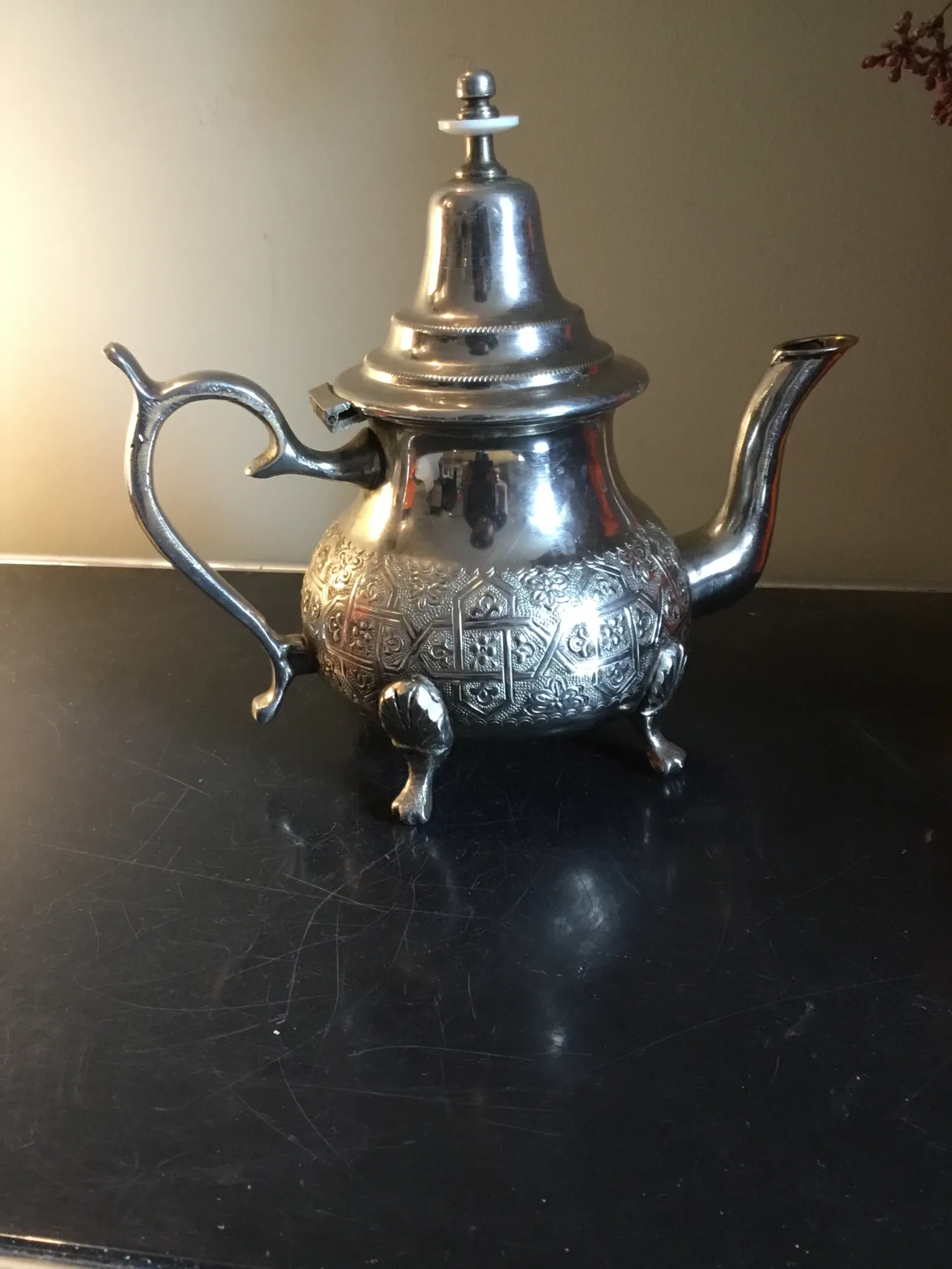 Traditional metal teapot with silver plating, Eastern style, on a stand.
