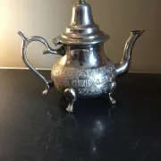 Traditional metal teapot with silver plating, Eastern style, on a stand.