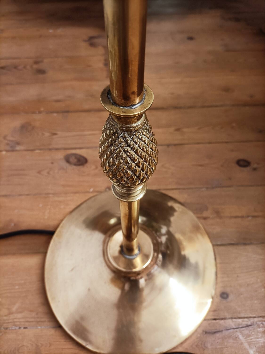 Bronze floor lamp with pine cone decoration.