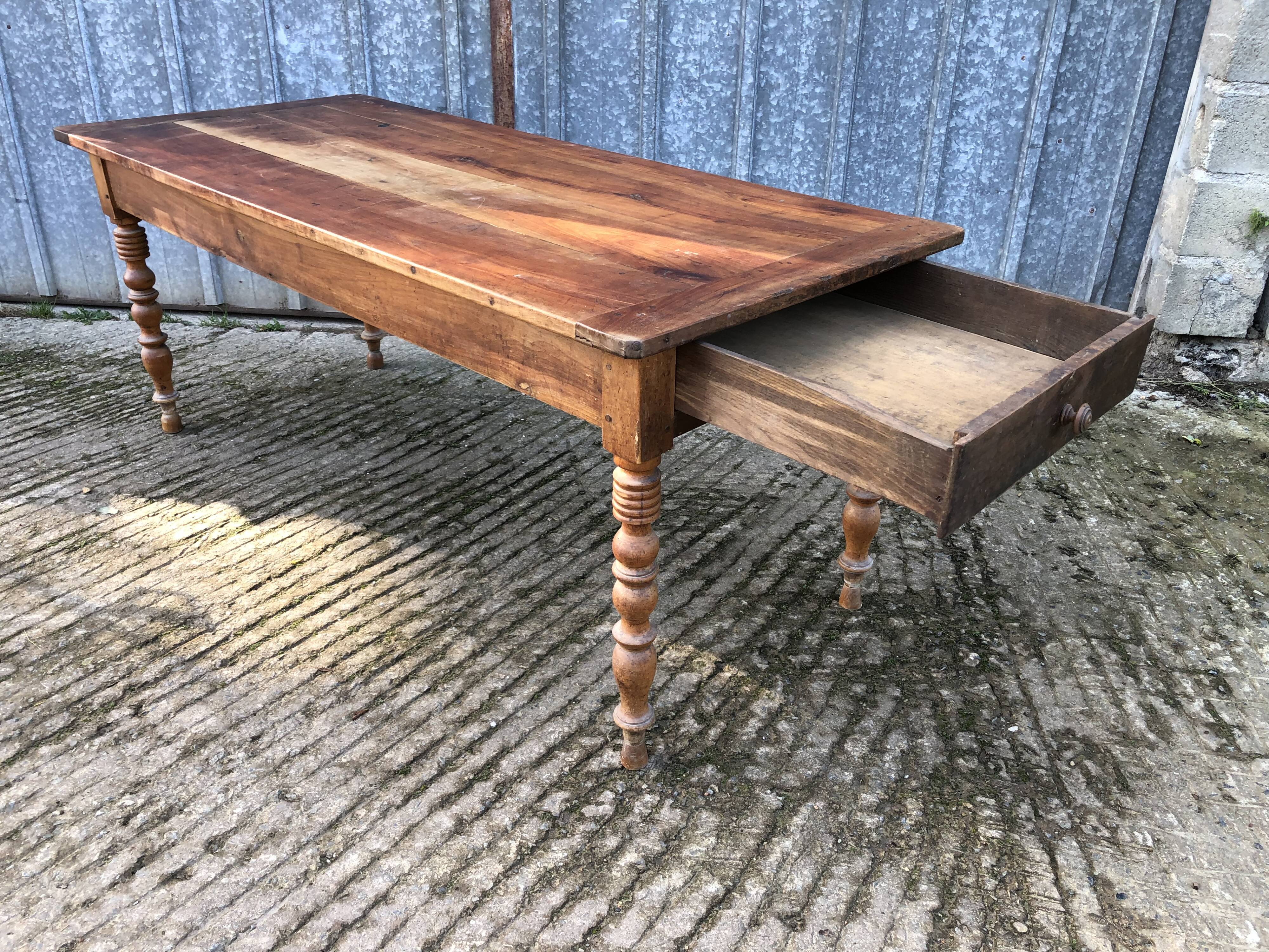 Antique farmhouse table in solid cherry wood with turned legs.