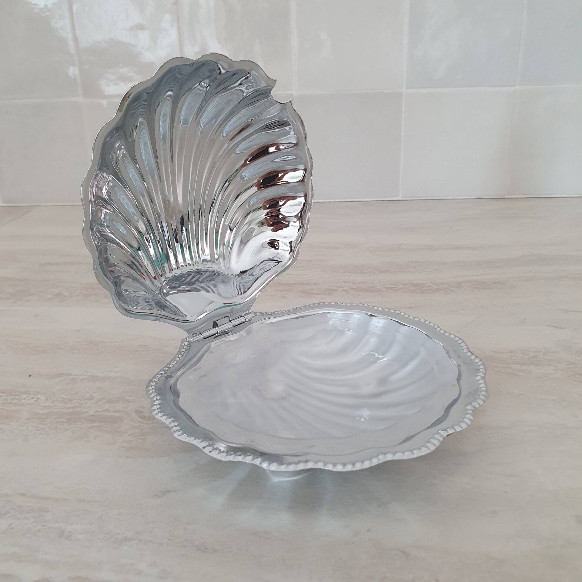Shell-shaped butter dish in stainless steel and white glass bowl.