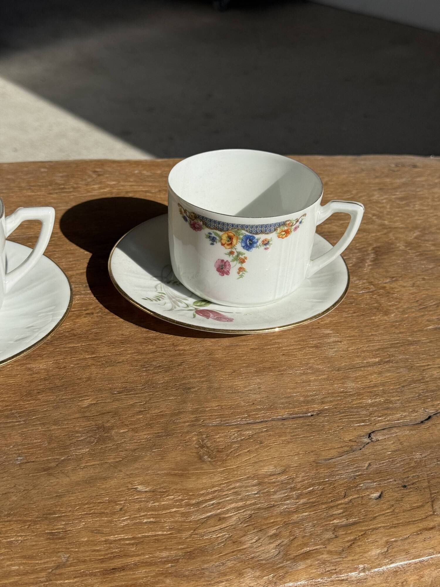 Pair of white porcelain cups from ADP France with a floral pattern and their s