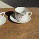 Pair of white porcelain cups from ADP France with a floral pattern and their s