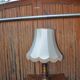 Vintage brown and gold desk lamp made of carved wood and brass, with a fringed shade.