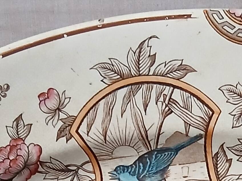 Large antique plate stamped with a fauna and flora pattern.