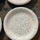 4 black speckled dessert plates on a vintage white background