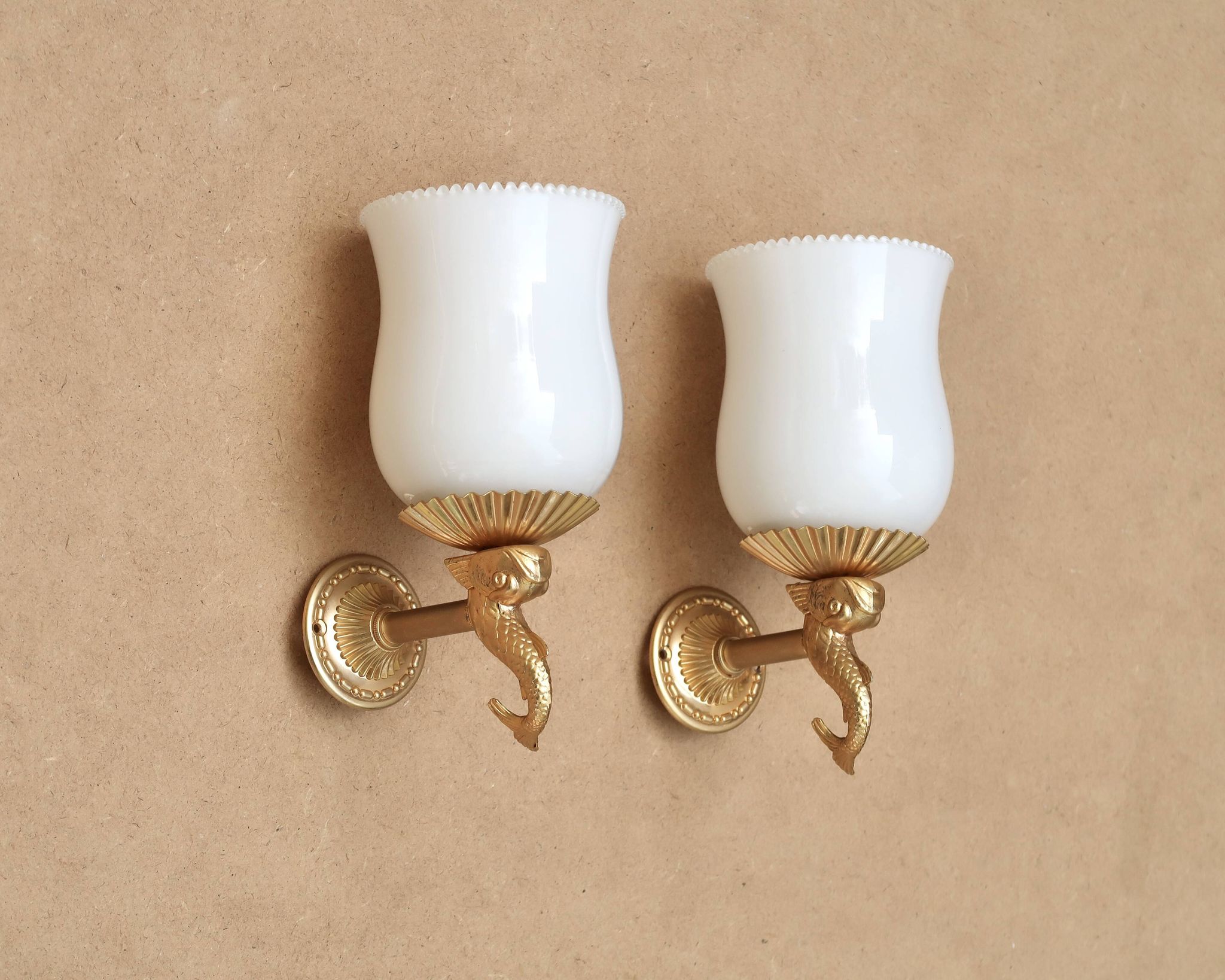 Pair of gold metal and opaque glass wall lights adorned with fish from the 1950s.