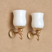 Pair of gold metal and opaque glass wall lights adorned with fish from the 1950s.