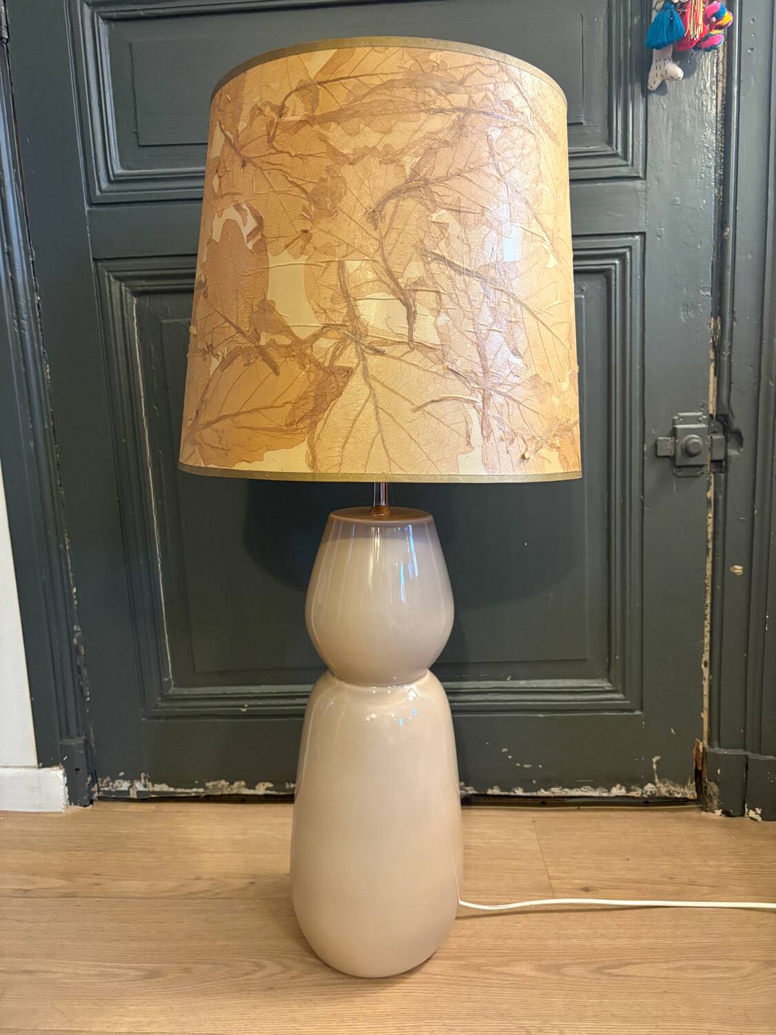 Large beige ceramic table lamp with a vintage shade.