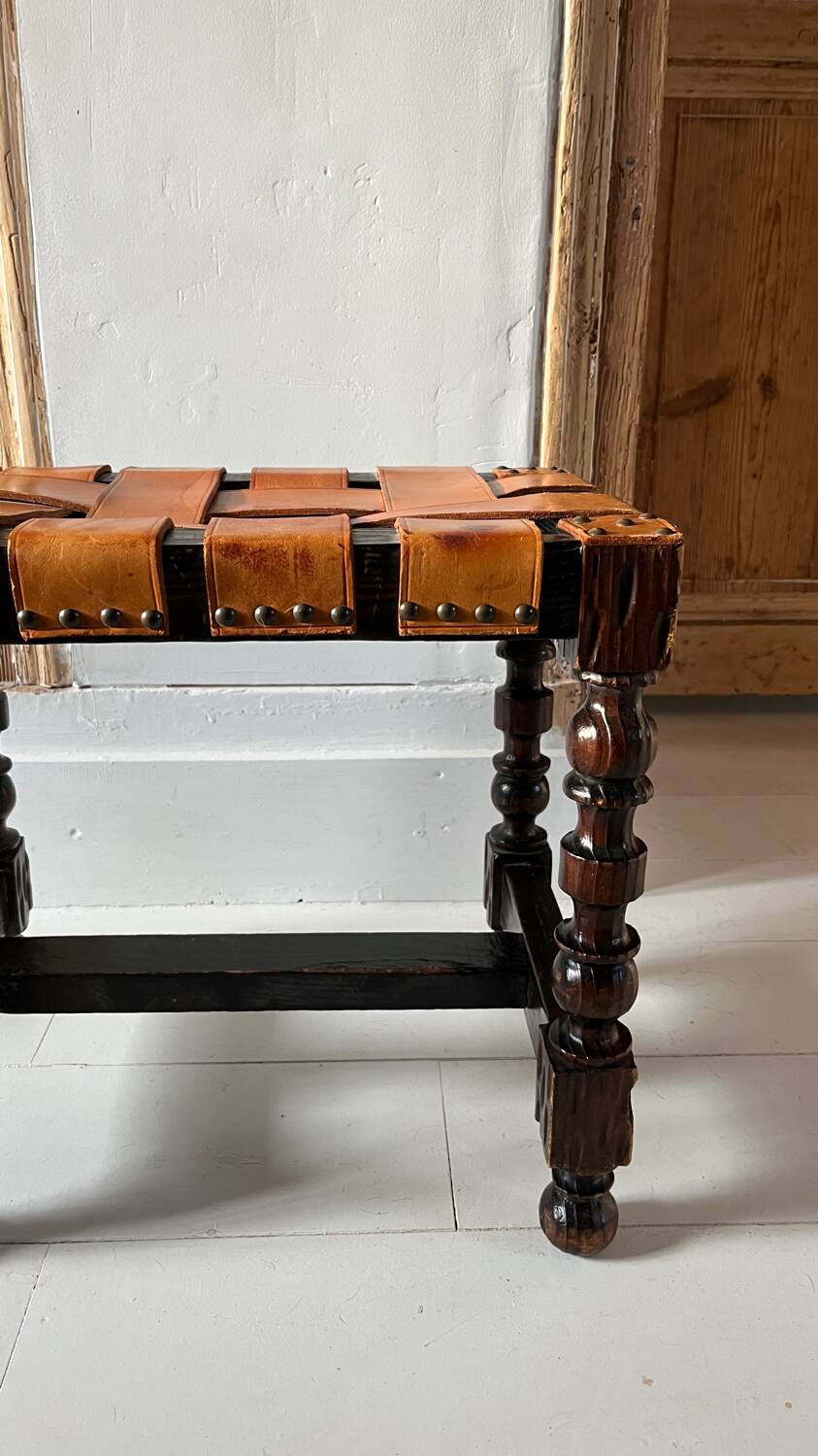 Antique turned wooden stool with woven leather.