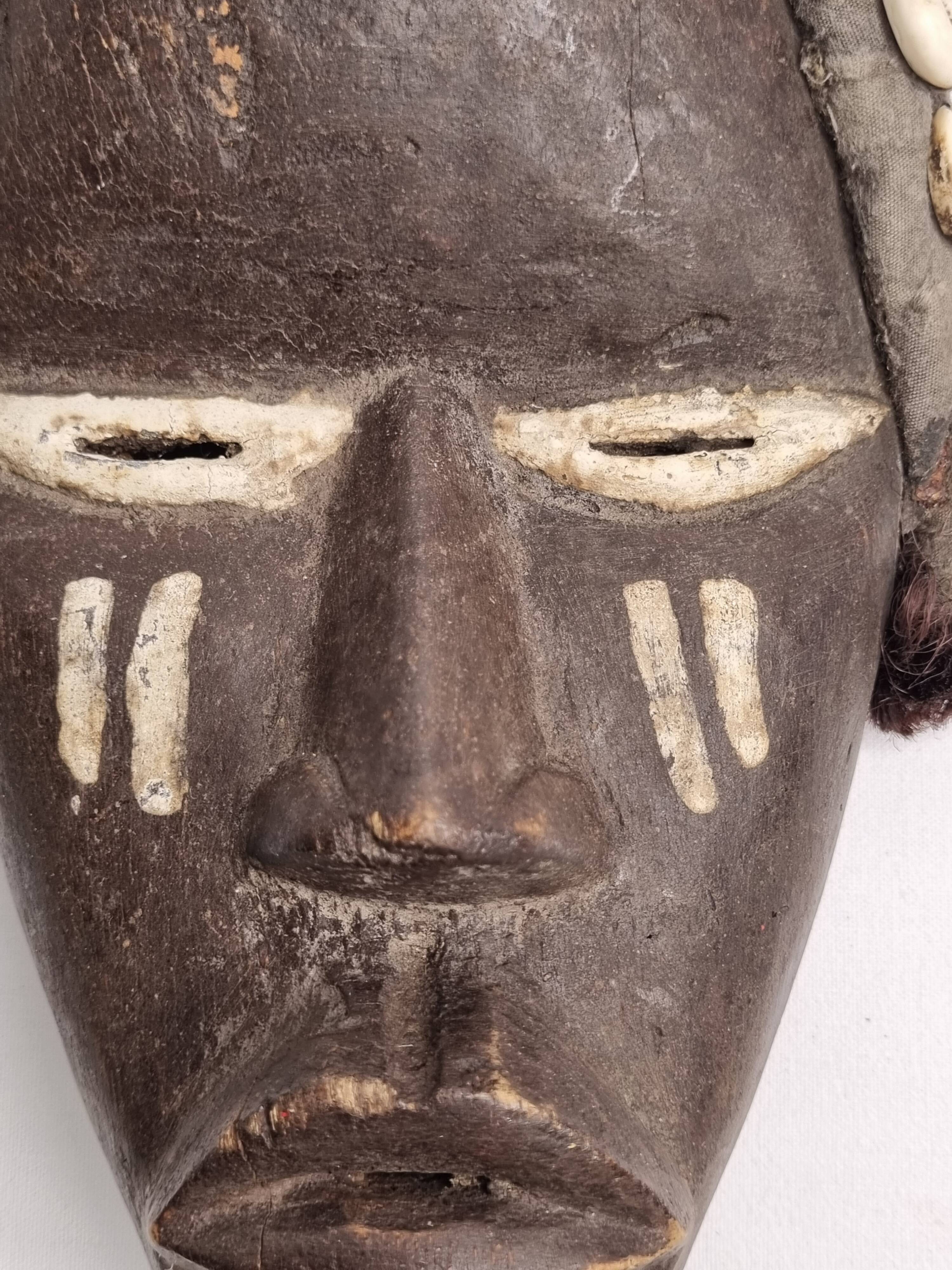 Tribal Dan mask in wood and cowrie shells, West Africa, 27 cm