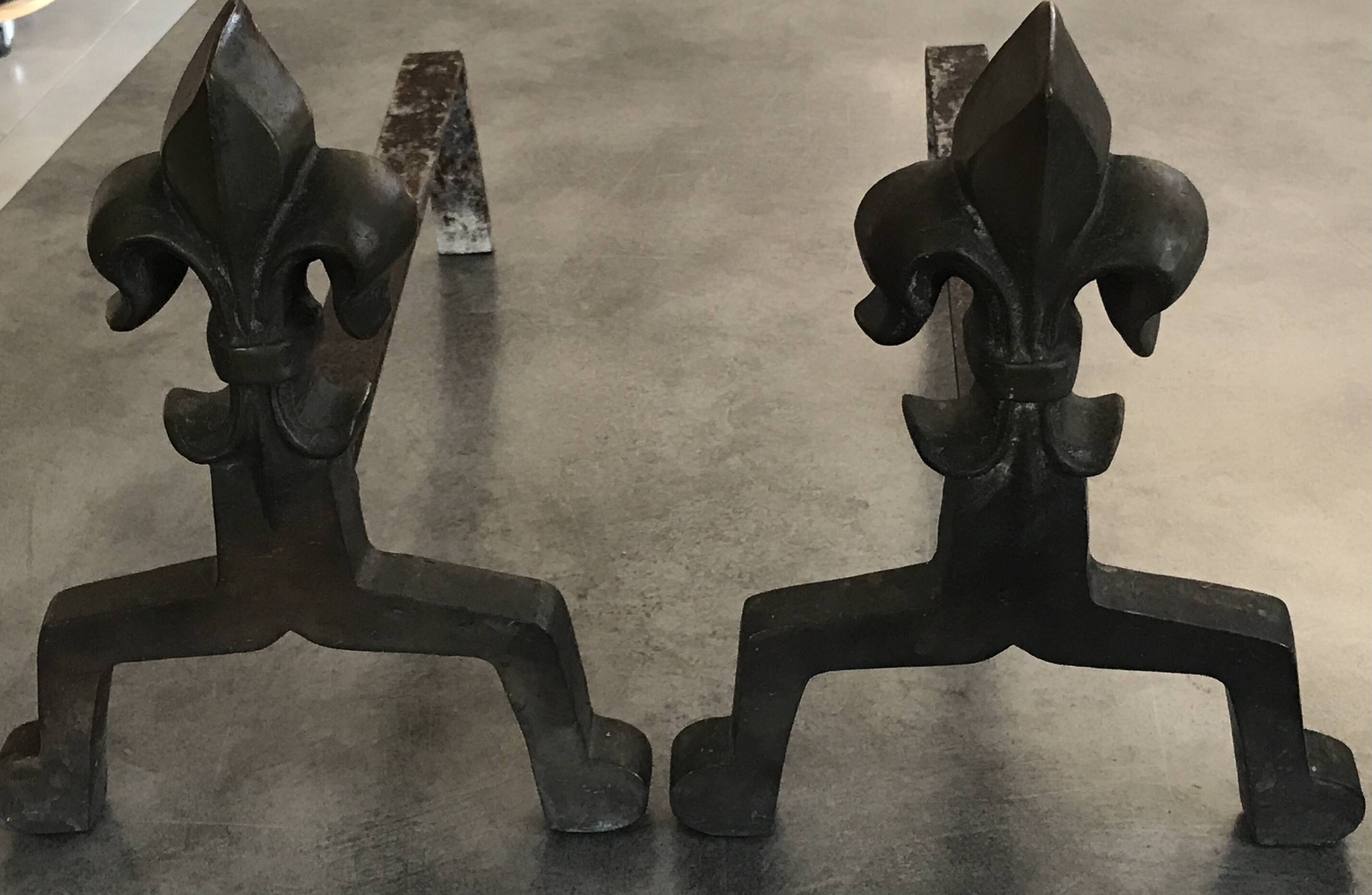 Pair of bronze fireplace firedogs with fleur-de-lys decor, art deco