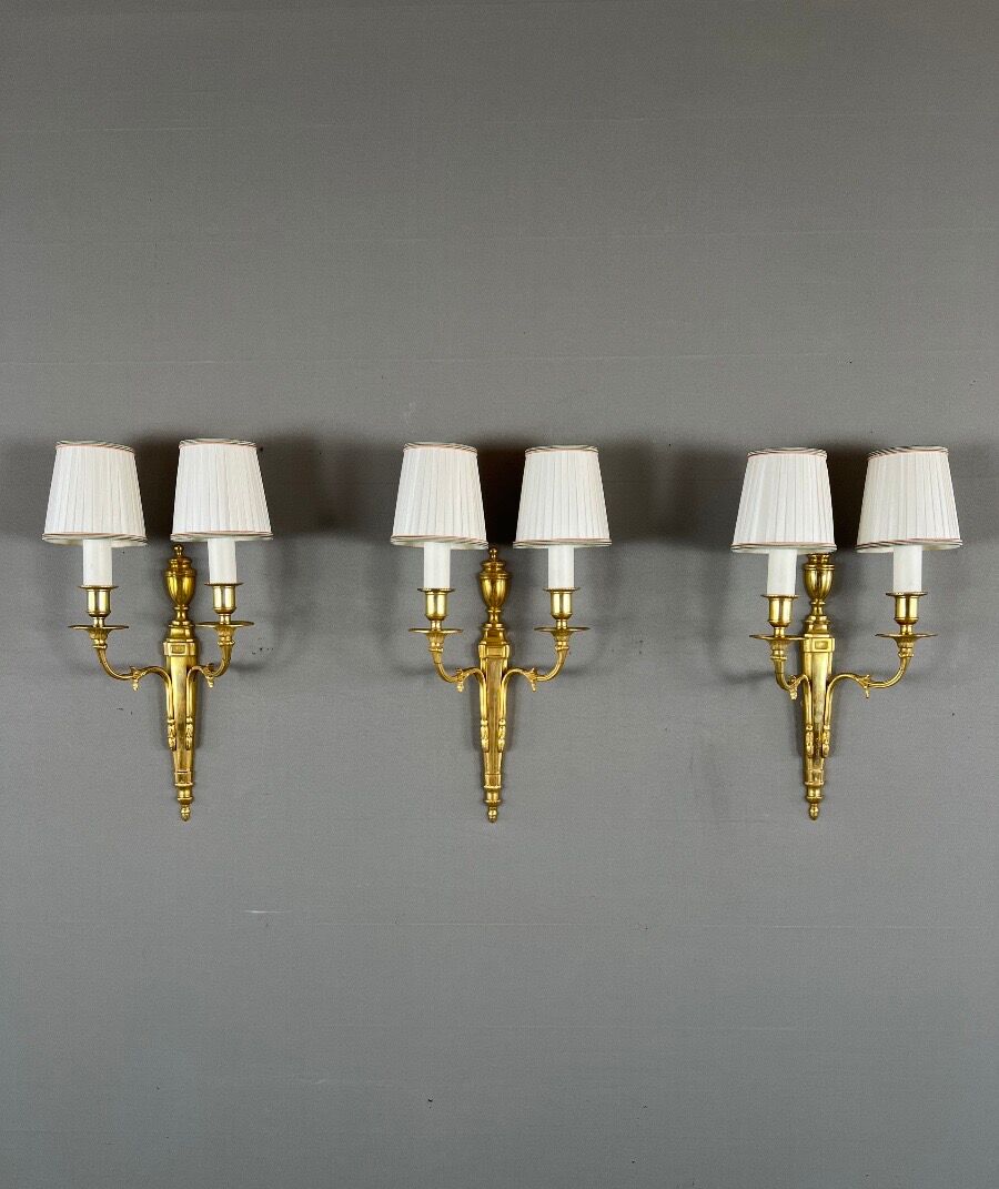 Set of three Louis XVI style wall sconces in gilded bronze, 20th century.