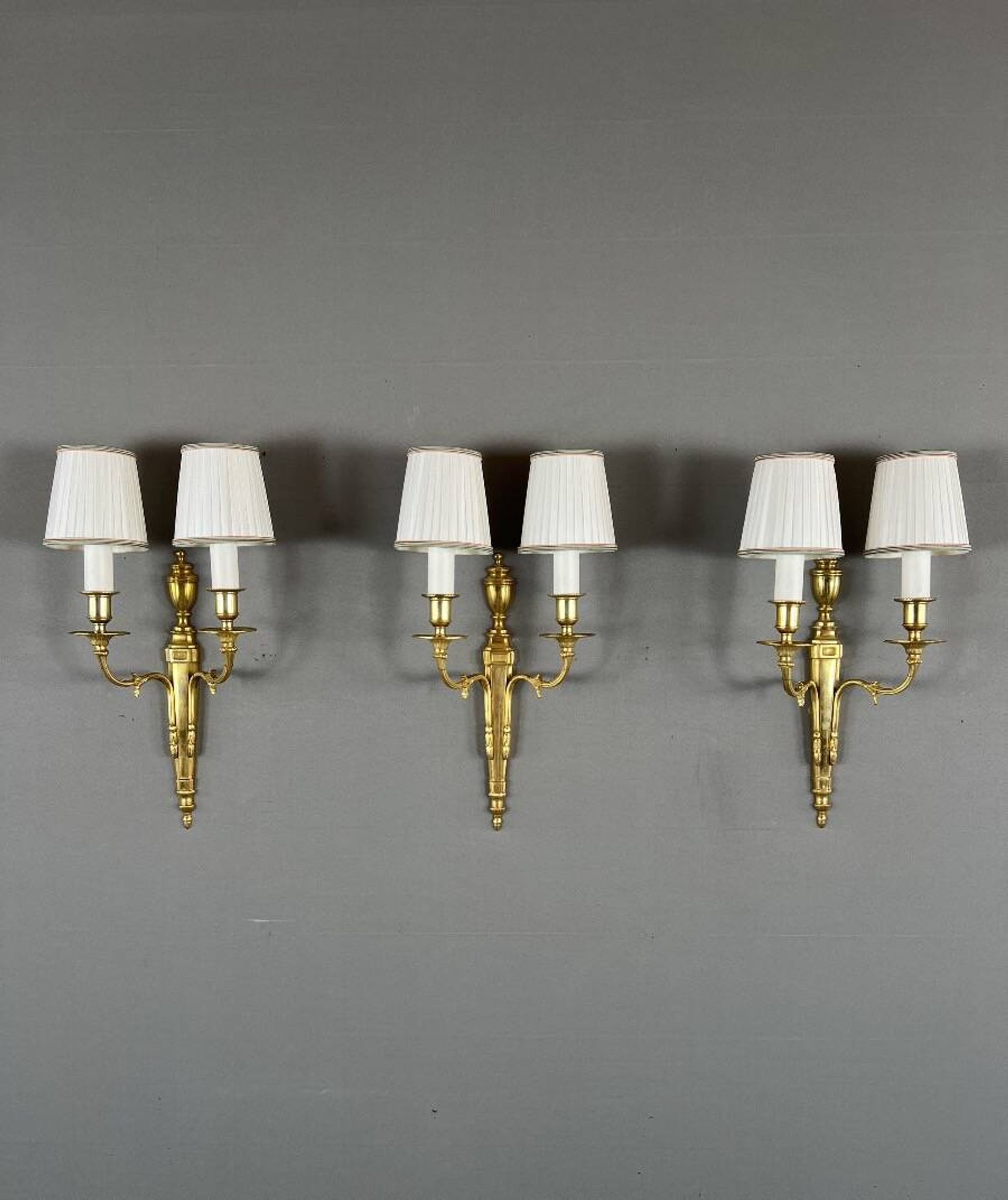Set of three Louis XVI style wall sconces in gilded bronze, 20th century.