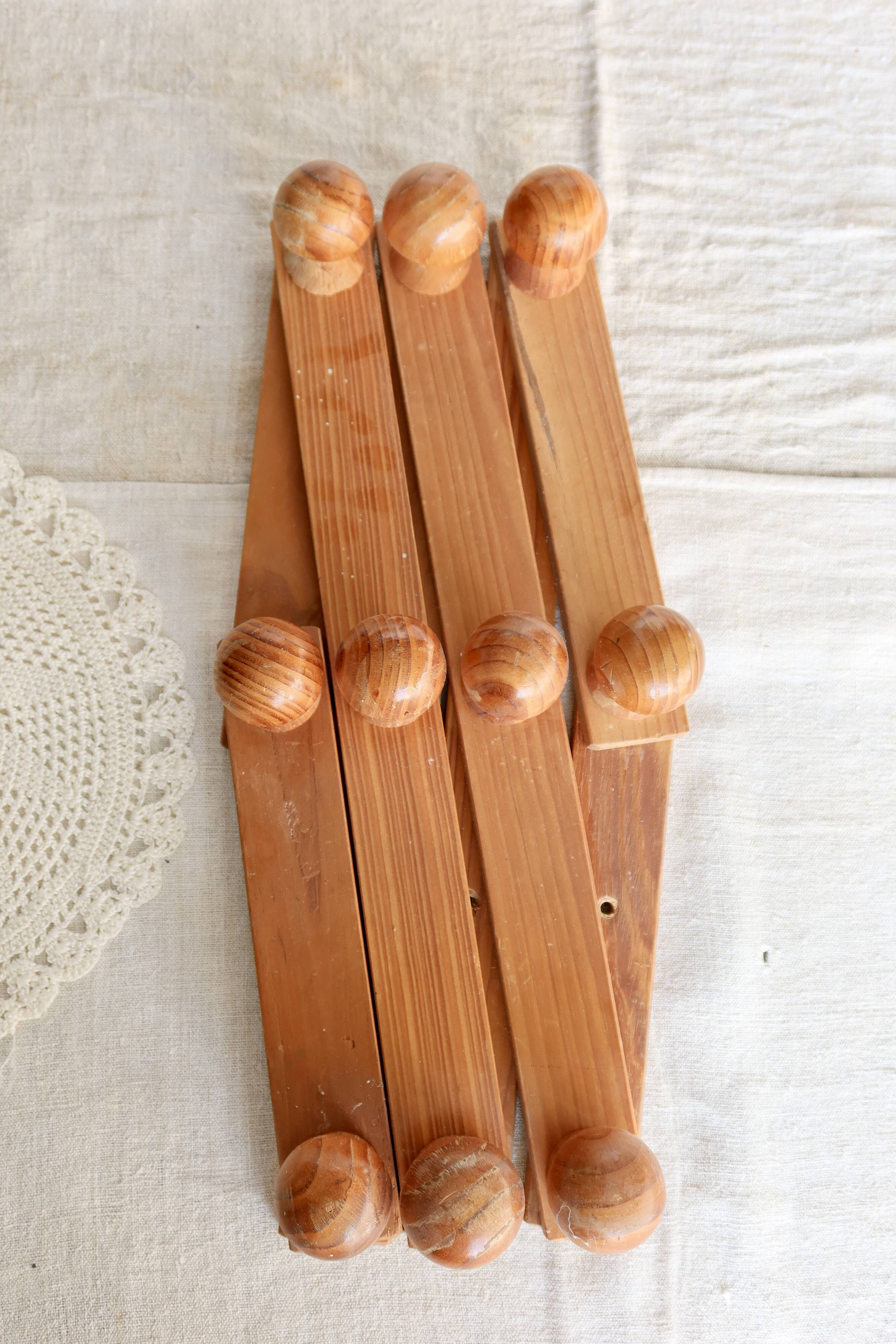 Antique wall-mounted coat rack accordion in dark pine, 10 wooden hooks.