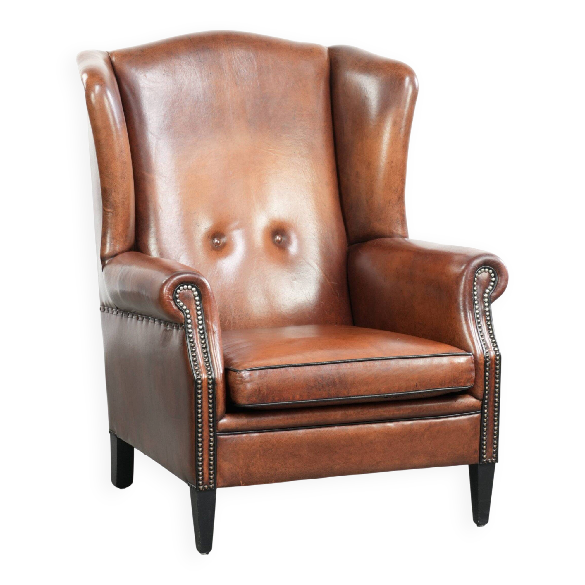 Sheepskin wingback armchair in a warm cognac colour with refined nailhead trim