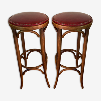 Pair of wooden bistro stools turned and sitting in 20th century red skai