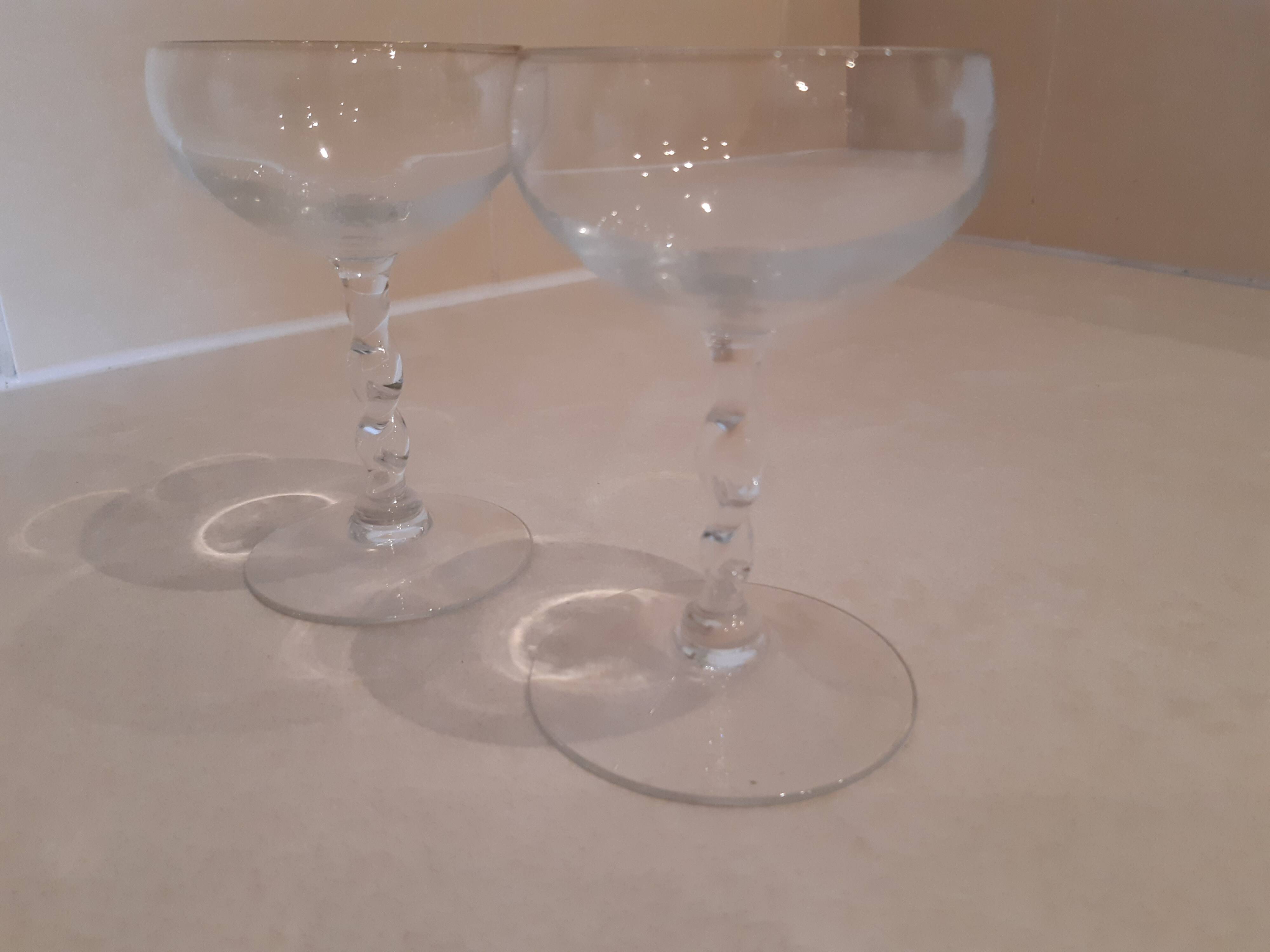 Two small crystal champagne glasses with twisted stems.