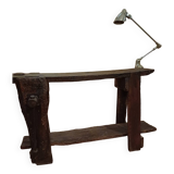 Small, very old, brutalist workbench equipped with a period workshop lamp